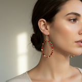 A pair of beaded hoop earrings with orange and turquoise beads, on a white background.