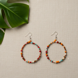A pair of beaded hoop earrings with orange and turquoise beads, on a white background.
