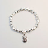 Silver beaded bracelet with a pineapple charm on a light gray background