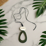 Necklace with a pendant on a marble surface with leaves