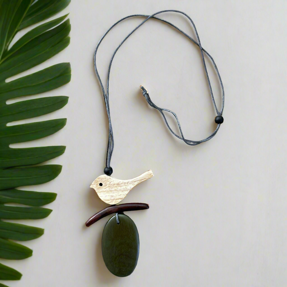 Necklace with a green pendant and wooden bird charm on a gray background