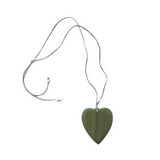 Heart-shaped pendant on a string against a gray fabric background