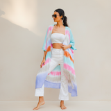 Woman in a colorful kimono standing on a rocky beach with ocean view