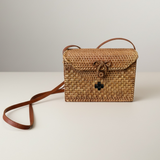 Woven rattan handbag with leather strap on a light background