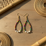 A pair of tear drop earrings featuring a combination of pearls and colorful seed beads, with a metallic hoop and hook design for wearing.