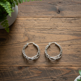 A pair of silver plate twist earrings with a hoop design, displayed against a white background.