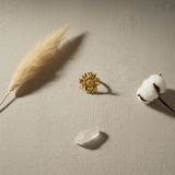 Gold sunflower-shaped earring on a white background