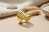 Gold ring with a ribbed design on a white background