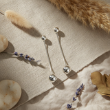 Silver ball earrings with chain drops on a white background