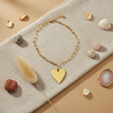 Gold heart-shaped pendant on a gold chain necklace against a white background