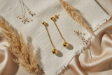 Pair of gold earrings with spherical ends on a white background