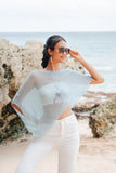 Suzie Blue Canada mint sheer mesh poncho worn by a woman on a beach with white pants and sunglasses.